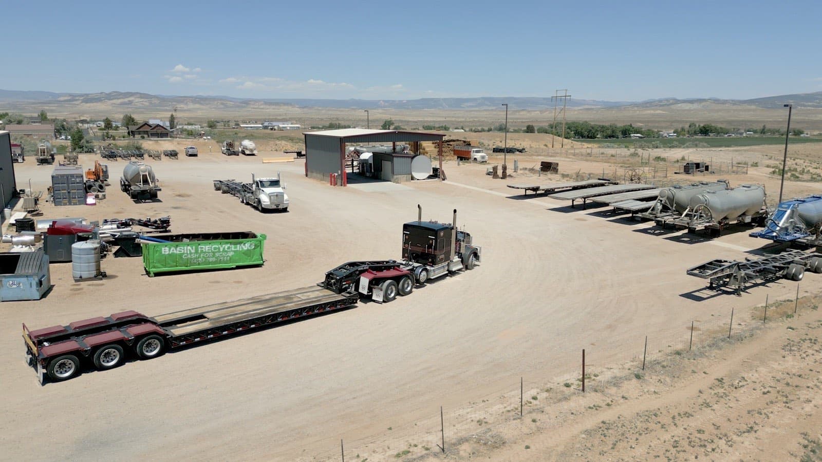 Aerial view of a working truck yard with a Kenworth and lowboy, flatbeds, and tankers parked across it